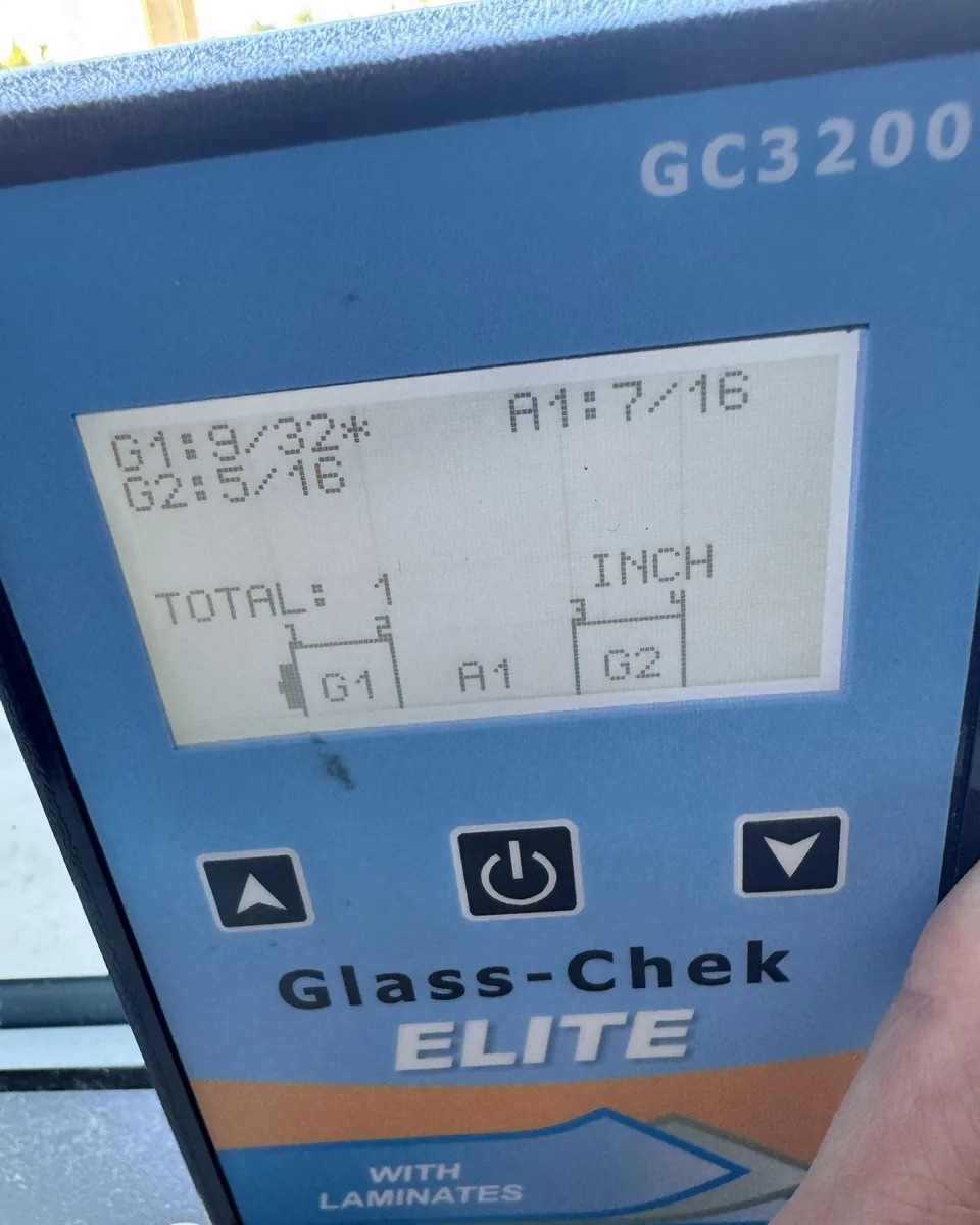 Glass-Chek Elite meter held against a window, showing glass and air gap thickness readings.