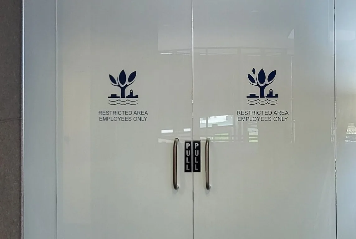Glass doors with frosted privacy film behind the City of Naperville logo and Restricted Area lettering.